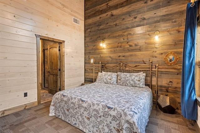 bedroom with visible vents, carpet flooring, and wooden walls