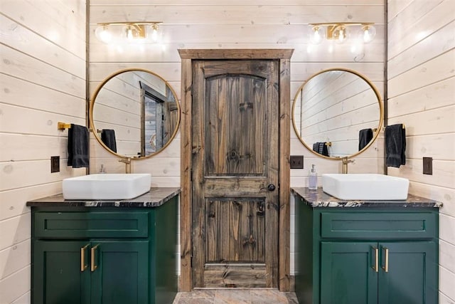 bathroom featuring wooden walls, two vanities, and a sink