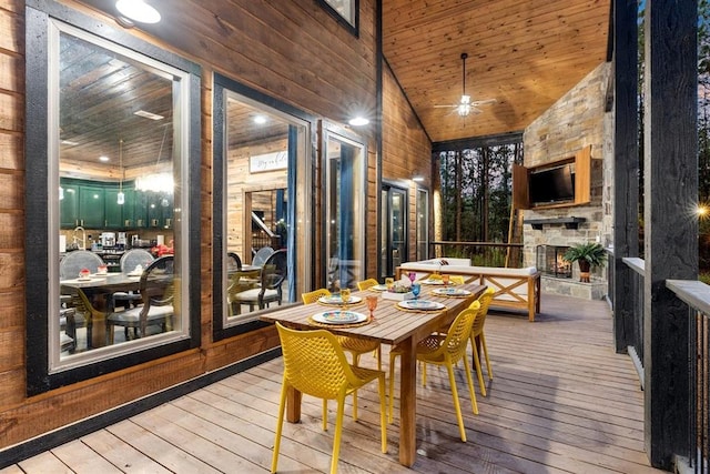 sunroom with wood ceiling, an outdoor stone fireplace, a ceiling fan, and vaulted ceiling