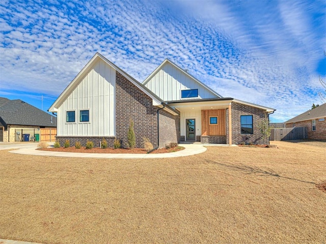 modern inspired farmhouse with brick siding, board and batten siding, and fence