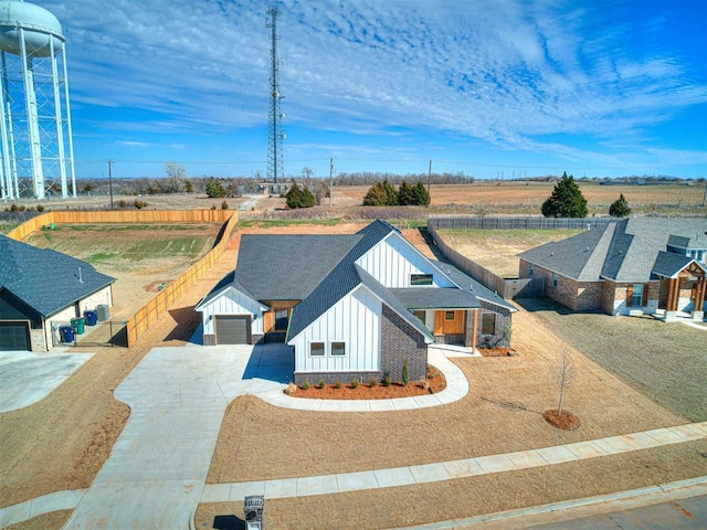 view of front facade featuring a shingled roof, concrete driveway, board and batten siding, fence, and a garage