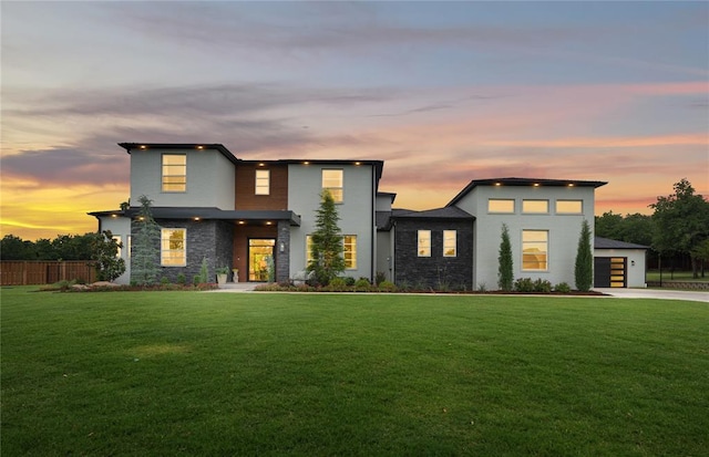 contemporary home featuring a garage, driveway, fence, and a yard