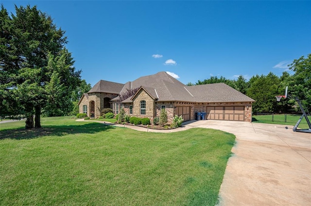 french country inspired facade featuring concrete driveway, an attached garage, fence, stone siding, and a front lawn