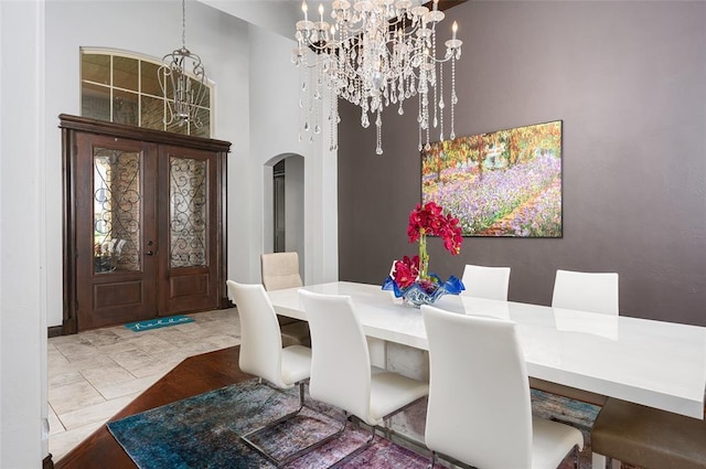 dining space featuring arched walkways, a chandelier, and french doors