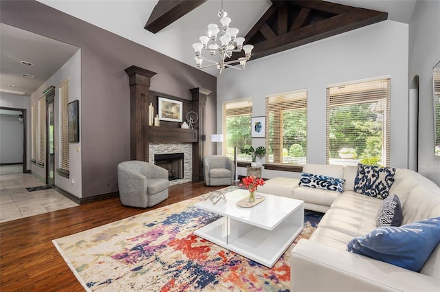 living area with a chandelier, wood finished floors, a fireplace, high vaulted ceiling, and beam ceiling