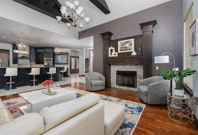 living area with an inviting chandelier, light wood finished floors, beamed ceiling, and a stone fireplace