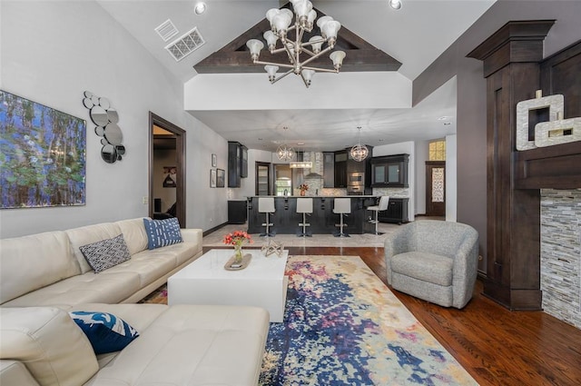 living area with high vaulted ceiling, visible vents, a chandelier, and wood finished floors