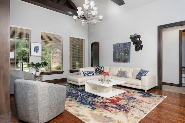 living area featuring arched walkways, baseboards, wood finished floors, and a notable chandelier