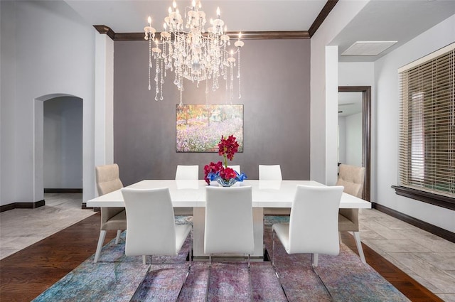 dining room featuring baseboards, arched walkways, wood finished floors, and ornamental molding