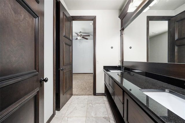 full bathroom with double vanity, marble finish floor, baseboards, and a sink