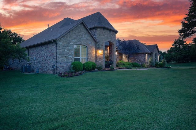 french provincial home with a shingled roof, central AC, and a front yard