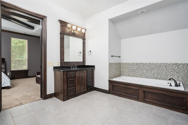 bathroom featuring ensuite bath, a garden tub, vanity, and baseboards