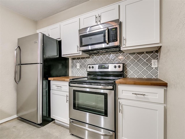 kitchen featuring stainless steel appliances, tasteful backsplash, wooden counters, and white cabinetry