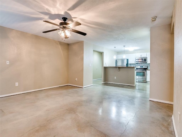 spare room featuring finished concrete flooring, ceiling fan, and baseboards