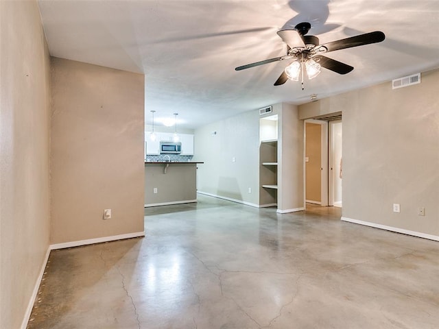 spare room featuring finished concrete flooring, baseboards, visible vents, and ceiling fan