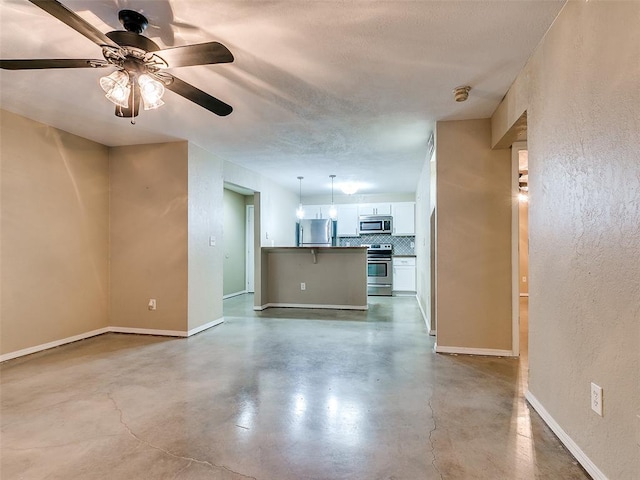 unfurnished living room with concrete flooring, a textured wall, a textured ceiling, and baseboards