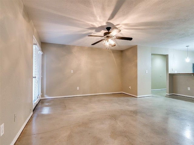 spare room featuring a ceiling fan, baseboards, finished concrete flooring, and a textured ceiling