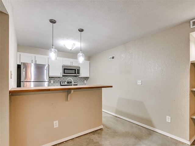 kitchen featuring stainless steel appliances, concrete floors, white cabinetry, backsplash, and decorative light fixtures