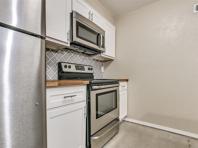 kitchen featuring stainless steel appliances, butcher block counters, white cabinetry, baseboards, and backsplash