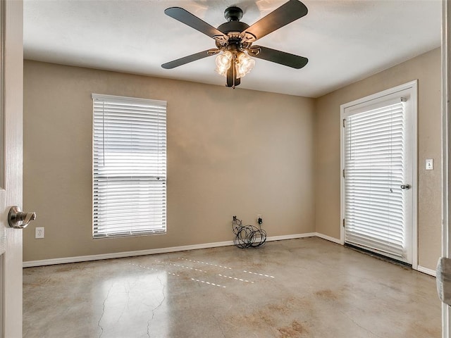 spare room with concrete floors, a ceiling fan, and baseboards