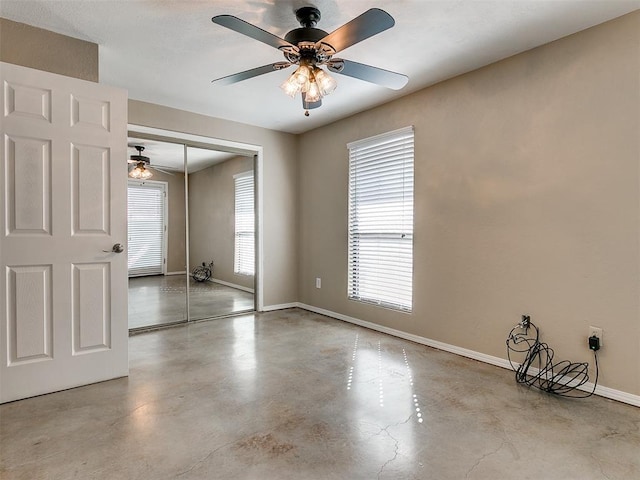 unfurnished room featuring concrete floors, baseboards, and ceiling fan