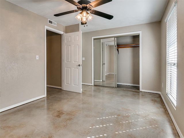 unfurnished bedroom with concrete flooring, multiple windows, visible vents, and baseboards
