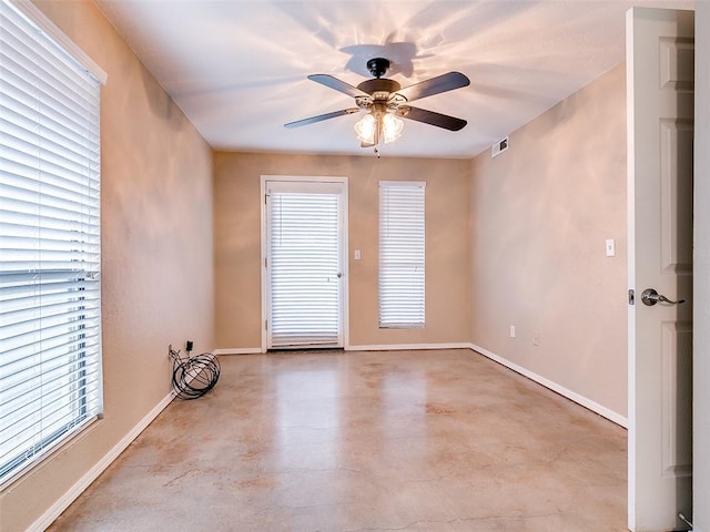 empty room with baseboards, concrete floors, visible vents, and ceiling fan