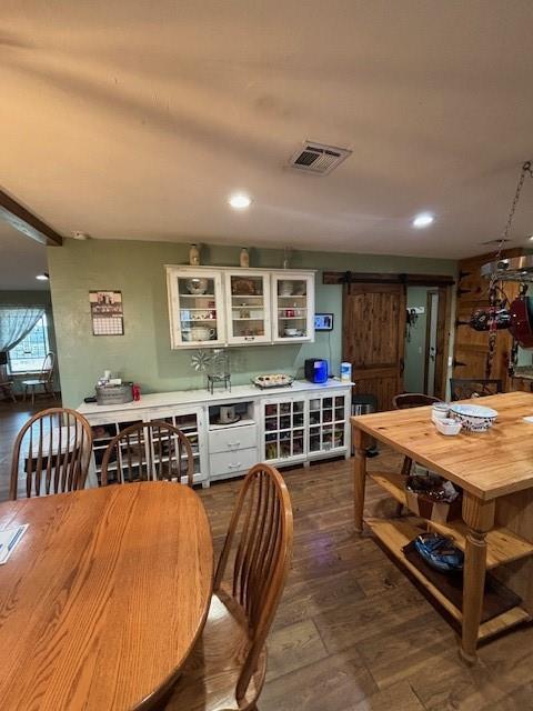 dining space featuring dark wood finished floors, visible vents, recessed lighting, and a barn door