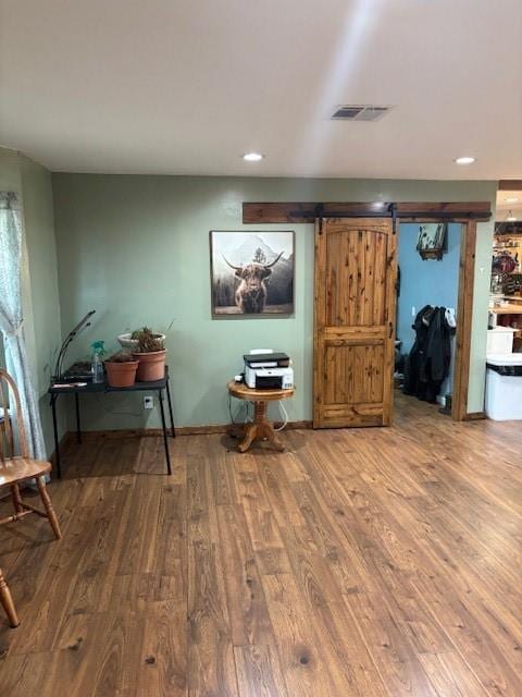 office area with visible vents, baseboards, a barn door, recessed lighting, and wood finished floors