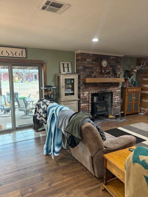 living area with visible vents, wood finished floors, and a wood stove