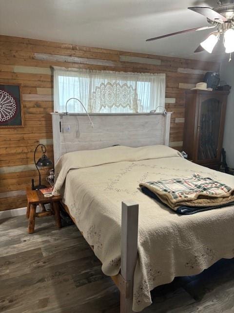 bedroom with wooden walls, multiple windows, wood finished floors, and ceiling fan