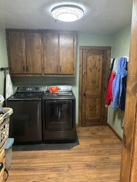 washroom featuring cabinet space, light wood-style floors, and washing machine and clothes dryer