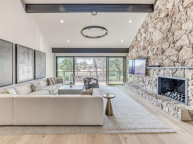 living room featuring beamed ceiling, high vaulted ceiling, wood finished floors, and a fireplace