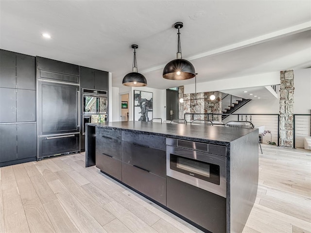 kitchen with hanging light fixtures, dark countertops, modern cabinets, and light wood-type flooring