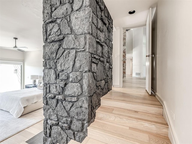 hall with visible vents, baseboards, and wood finished floors