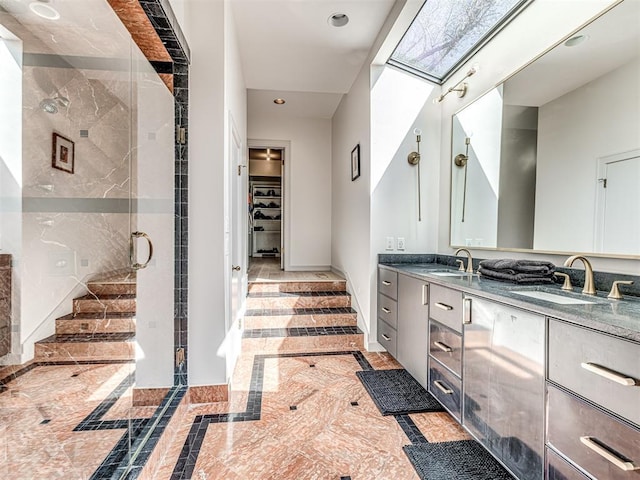 bathroom with double vanity, a spacious closet, a stall shower, and a sink