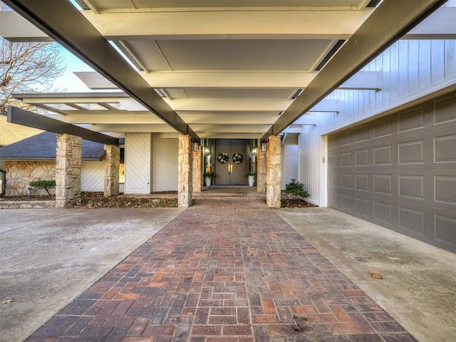 view of exterior entry featuring stone siding, decorative driveway, and a garage