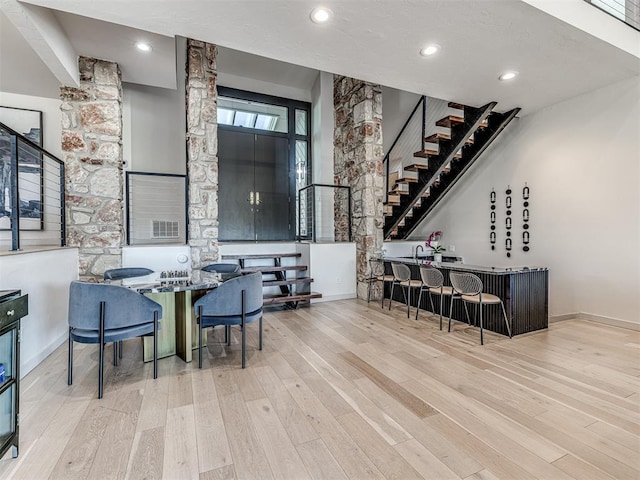 dining room with wet bar, stairway, wood finished floors, and baseboards