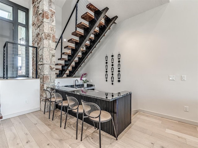 bar featuring indoor wet bar, wood finished floors, and baseboards