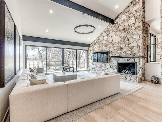 living area with beam ceiling, high vaulted ceiling, wood finished floors, recessed lighting, and a stone fireplace