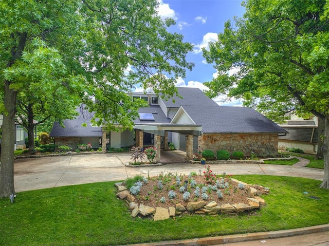 3108 Brush Creek Rd, Oklahoma City, OK 73120 - view of front of home featuring concrete driveway, stone siding, an attached carport, a front lawn, and a shingled roof