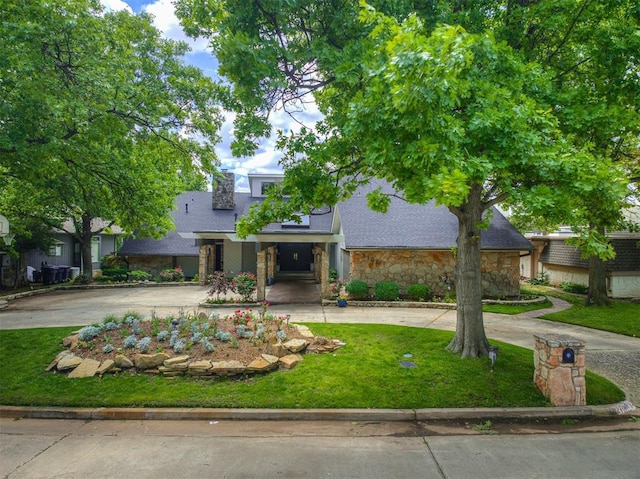 3108 Brush Creek Rd, Oklahoma City, OK 73120 - view of front of home featuring curved driveway, stone siding, a front lawn, a chimney, and a shingled roof