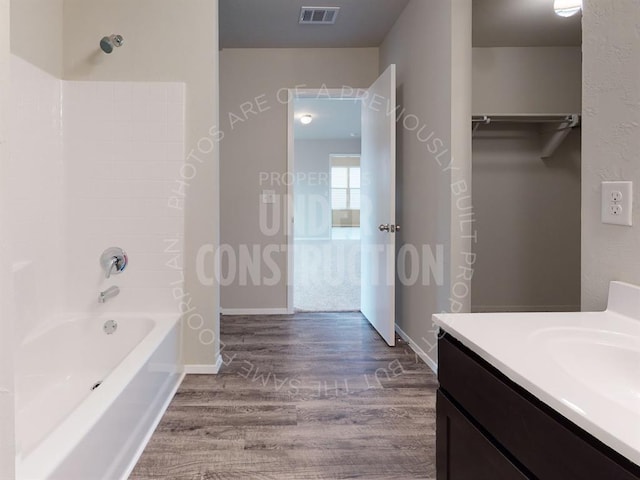 full bath with baseboards, visible vents, wood finished floors, vanity, and shower / bathing tub combination