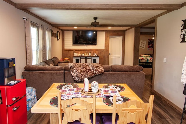 dining space featuring ceiling fan, beamed ceiling, wood finished floors, and wooden walls