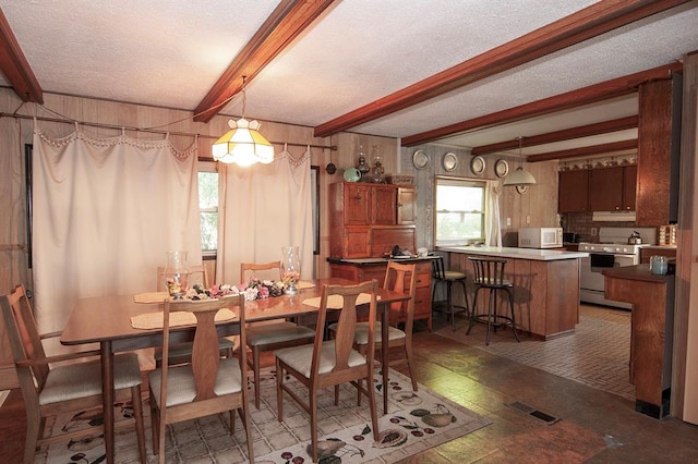 dining room featuring wooden walls, beam ceiling, visible vents, and a textured ceiling