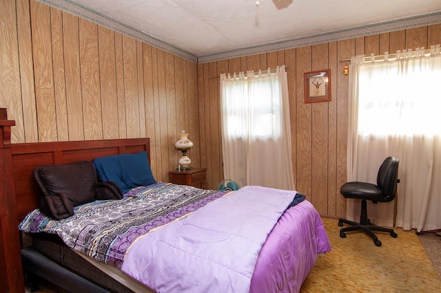 carpeted bedroom featuring ceiling fan, ornamental molding, multiple windows, and wooden walls