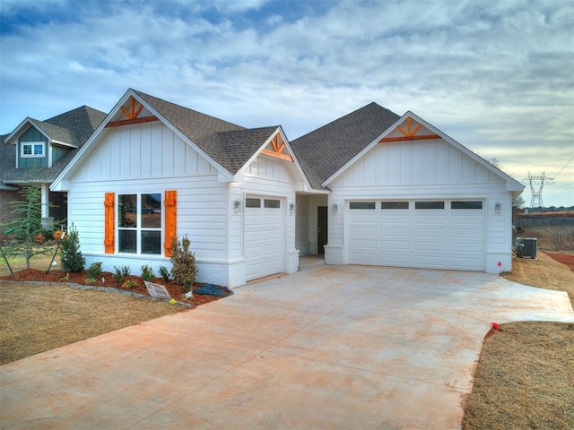 view of front of property featuring roof with shingles, concrete driveway, central AC unit, board and batten siding, and a garage