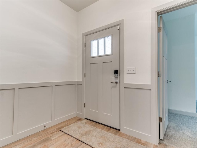 entrance foyer featuring a wainscoted wall, a decorative wall, and wood finished floors