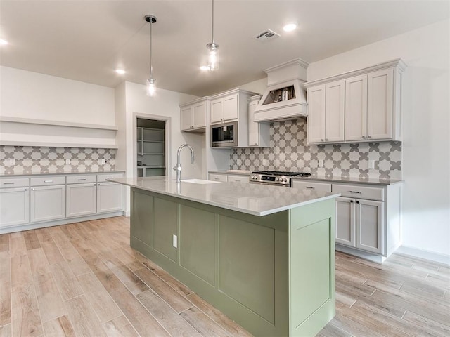 kitchen with stainless steel appliances, light countertops, backsplash, light wood-style flooring, and a sink