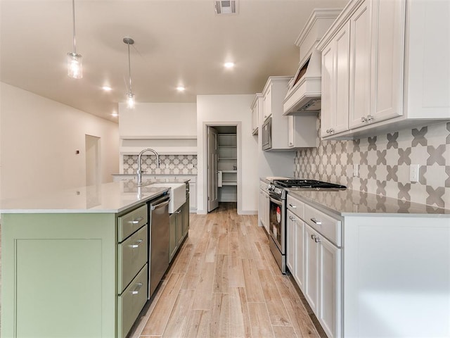 kitchen with stainless steel appliances, visible vents, white cabinets, light wood-type flooring, and custom range hood